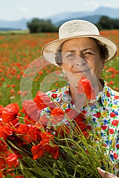 Senior woman picking flowers on the poppy field