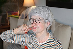 Senior woman picking her nose at home