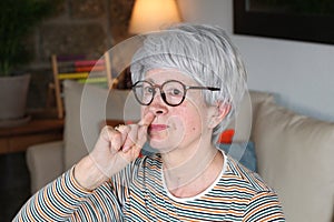 Senior woman picking her nose at home