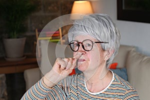 Senior woman picking her nose at home