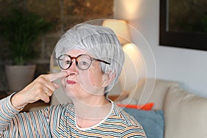 Senior woman picking her nose at home