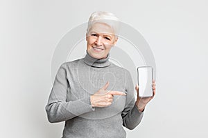 Senior woman pointing at smartphone screen mockup copy space