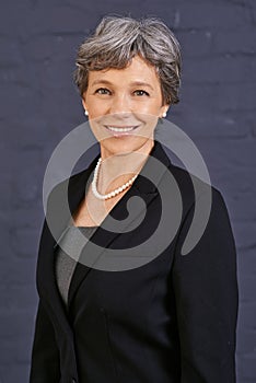 Senior woman, portrait and corporate professional with smile, pride and ambition on wall background. Management
