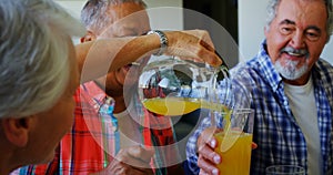 Senior woman pouring juice into glass to her friend 4k