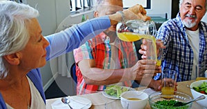 Senior woman pouring juice into glass to her friend 4k