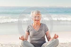 Senior woman practicing yoga on the beach