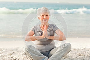 Senior woman practicing yoga on the beach