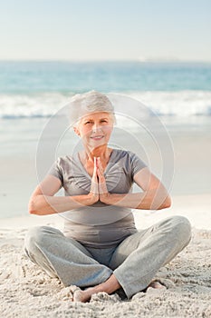 Senior woman practicing yoga on the beach