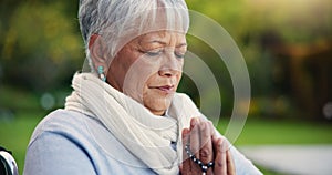 Senior woman, praying hands or rosary in wheelchair in nature, faith or hope in retirement. Mature person, catholic or