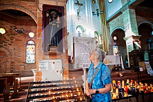 Senior woman praying to the Famous miraculous statuette of San Antonio de Arma in the