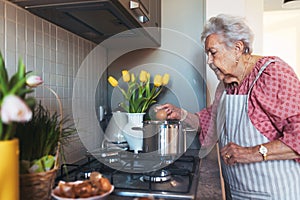 Senior woman preparing traditional easter meals for family, boiling eggs. Recreating family traditions and customs.