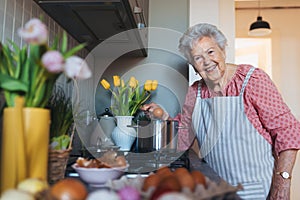 Senior woman preparing traditional easter meals for family, boiling eggs. Recreating family traditions and customs.