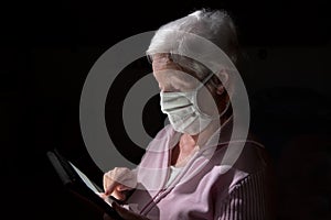 Senior woman with protective mask chats with tablet computer