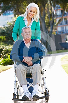 Senior Woman Pushing Husband In Wheelchair