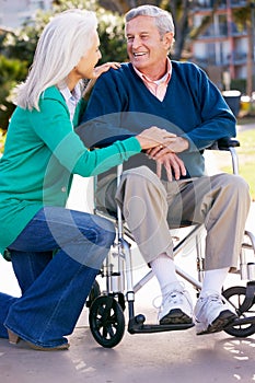 Senior Woman Pushing Husband In Wheelchair