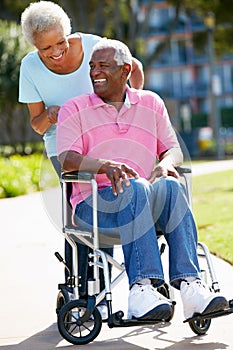 Senior Woman Pushing Husband In Wheelchair