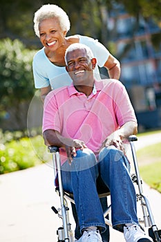 Senior Woman Pushing Husband In Wheelchair