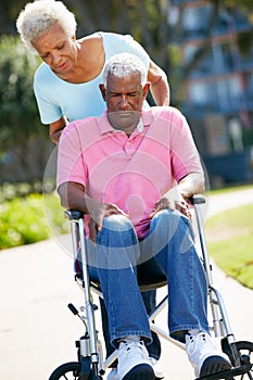 Senior Woman Pushing Unhappy Husband In Wheelchair