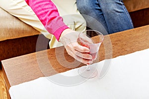 Senior woman put glass of wine on table