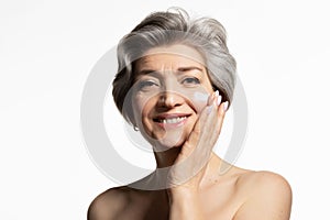 Senior woman putting cosmetic  creme on face.