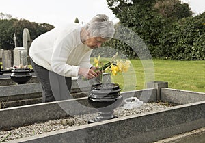 Senior woman putting flowers on a grave