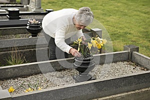 Senior woman putting flowers on a grave