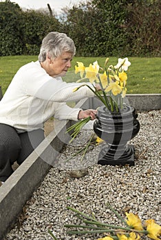 Senior woman putting flowers on a grave