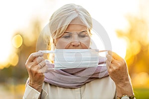 Senior woman putting on a protective mask