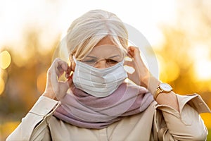 Senior woman putting on a protective mask