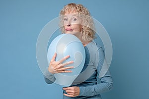 Senior woman r holding a blue balloon being alone on her Birthday party