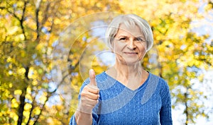 Senior woman r showing thumbs up in autumn park