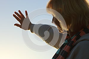 Senior woman reaching out to the sun