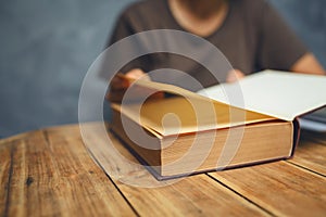 Senior woman reading a book at living room with old vintage table and concrete wall background.