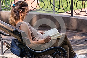 Tranquil Moments: Senior Woman Reading Book on Balcony Bench in Spa Resort