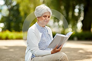 Senior woman reading book at summer park