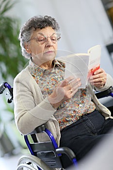 Senior woman reading a book in a wheelchair