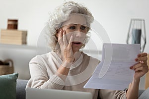 Senior woman reading letter feels disappointed having financial problems