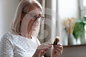 Senior woman reading medicines instruction on pills bottle