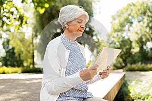 Senior woman reading newspaper at summer park