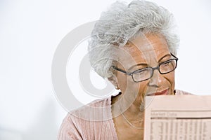 Senior Woman Reading Stocks And Shares In Newspaper