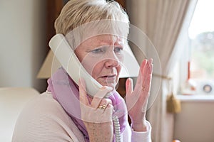 Senior Woman Receiving Unwanted Telephone Call At Home photo