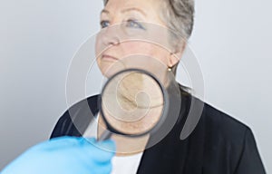 Senior woman at the reception of a facial plastic surgeon. Consultation on the removal of age wrinkles on the face. Doctor shows