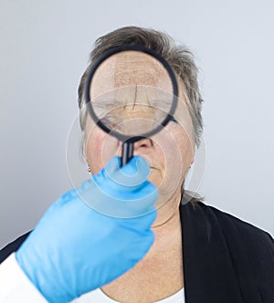 Senior woman at the reception of a facial plastic surgeon. Consultation on the removal of age wrinkles on the face. Doctor shows