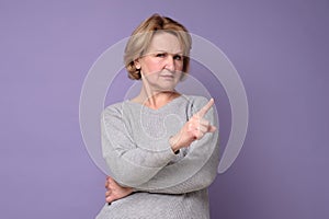 Senior woman with rejection expression doing negative sign saying no. photo