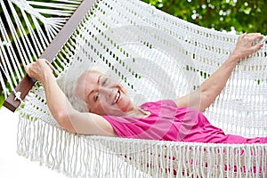 Senior Woman Relaxing In Beach Hammock