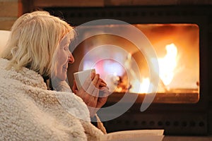 Senior woman relaxing by fireplace