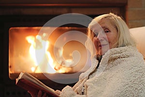 Senior woman relaxing by fireplace