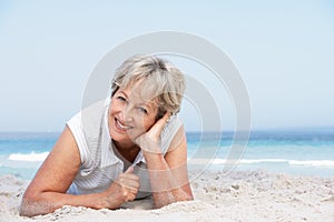 Senior Woman Relaxing On Sandy Beach