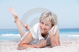 Senior Woman Relaxing On Sandy Beach