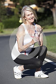 Senior Woman Resting And Drinking Water After Exercise